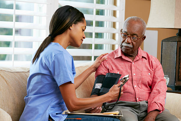 nurse visiting senior male patient at home taking blood pressure